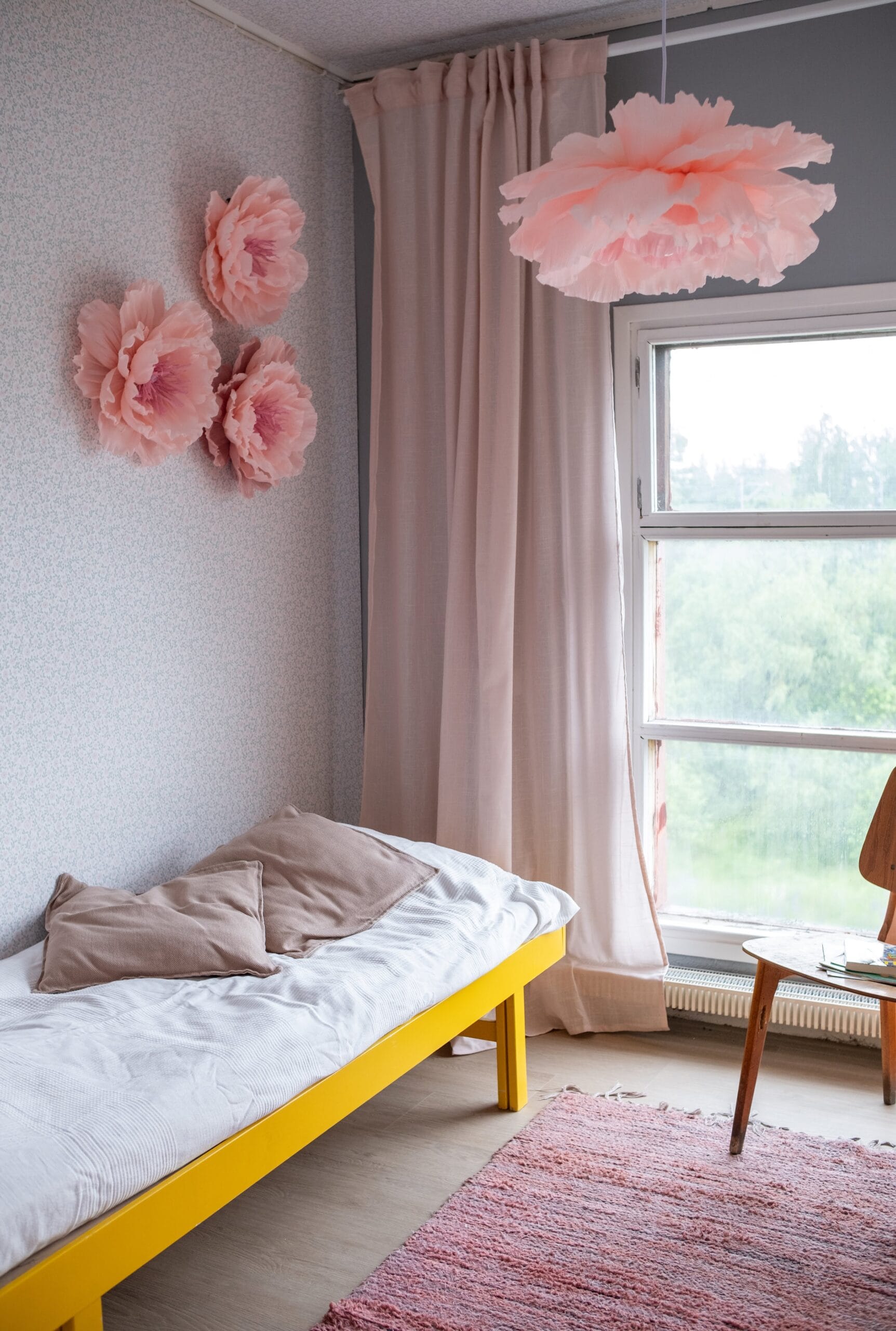 Tapetissa on pieniä vaaleanpunaisia kukkia ja vihreitä lehtiä valkoisella pohjalla.