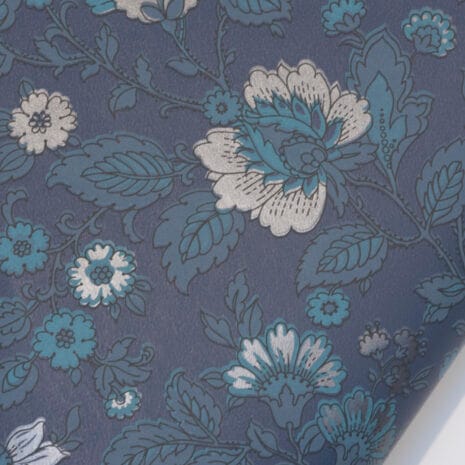 Sinikka tummansininen Tapetissa on tummia, petroolin- ja harmaansinisen sävyisiä kukkia tummansinisellä pohjalla.