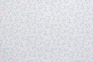 Tapetissa on pieniä vaaleanpunaisia kukkia ja vihreitä lehtiä valkoisella pohjalla.